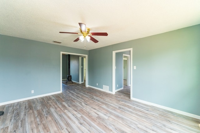 unfurnished room with baseboards, a ceiling fan, light wood finished floors, and visible vents