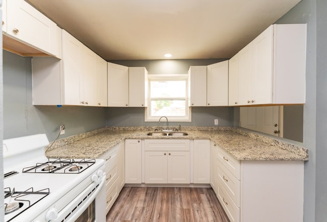 kitchen with white cabinets, a sink, gas range gas stove, light wood-style flooring, and recessed lighting