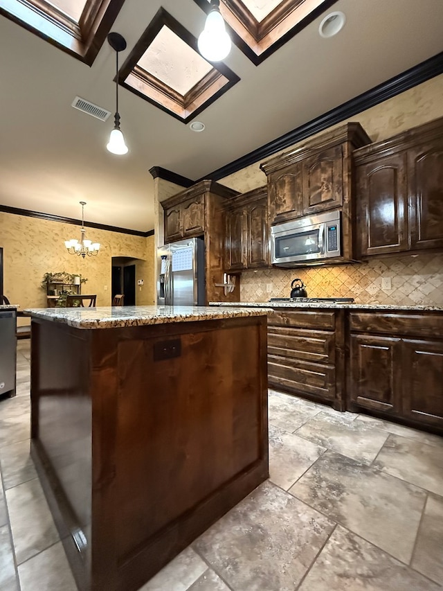 7802 Sienna Dr, Odessa, TX 79765 - kitchen featuring appliances with stainless steel finishes, ornamental molding, a center island, light stone counters, and a skylight