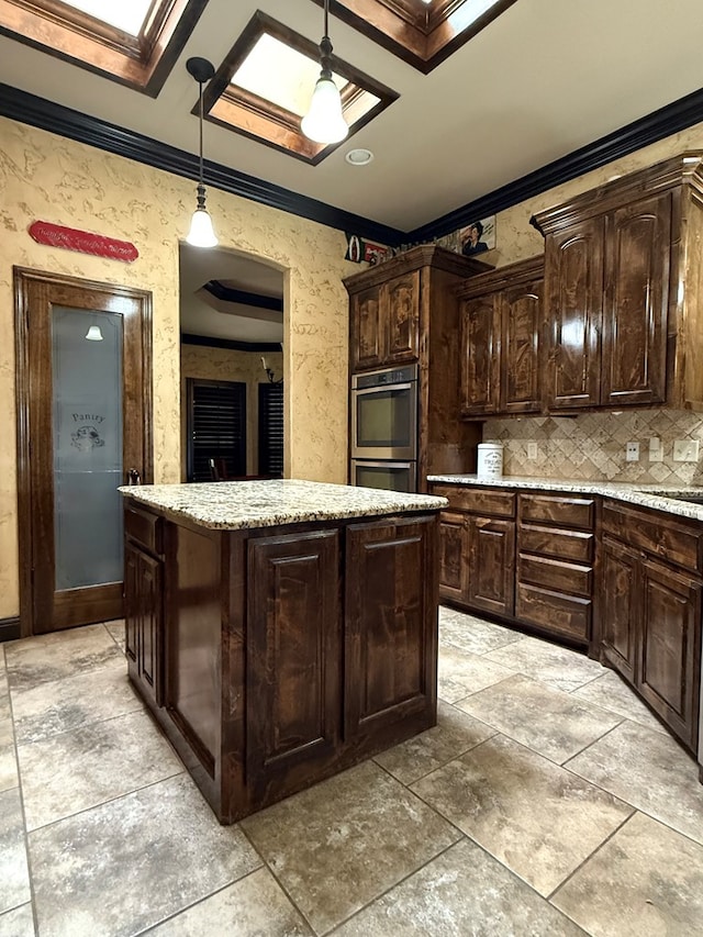 7802 Sienna Dr, Odessa, TX 79765 - kitchen featuring ornamental molding, double oven, a center island, dark brown cabinetry, and hanging light fixtures