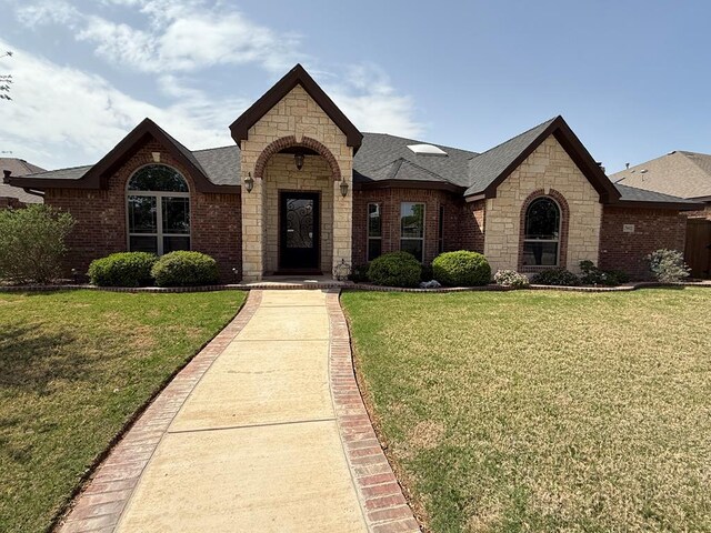 7802 Sienna Dr, Odessa, TX 79765 - view of front facade with stone siding, a front yard, and roof with shingles