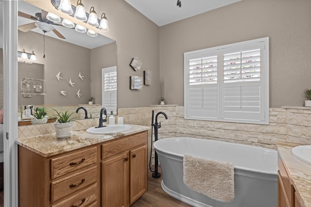 3960 Rabb St, Odessa, TX 79762 - bathroom with a freestanding tub, vanity, healthy amount of natural light, ceiling fan, and tile walls
