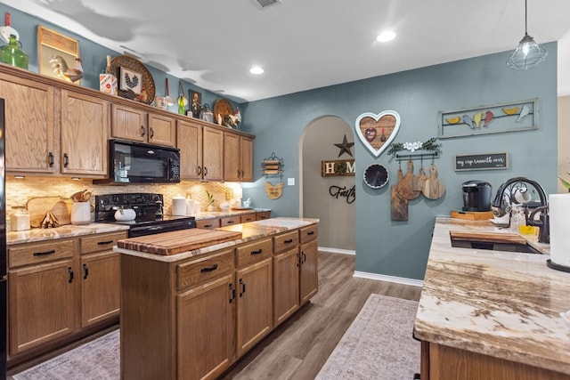 3960 Rabb St, Odessa, TX 79762 - kitchen with black appliances, decorative backsplash, arched walkways, a kitchen island, and dark wood finished floors