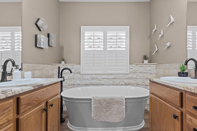 3960 Rabb St, Odessa, TX 79762 - full bathroom featuring tile walls, two vanities, a soaking tub, and a wainscoted wall