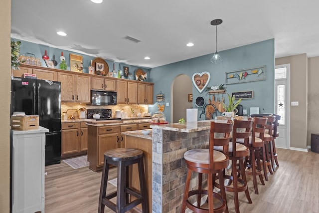 3960 Rabb St, Odessa, TX 79762 - kitchen with black appliances, an island with sink, light wood-style floors, backsplash, and arched walkways