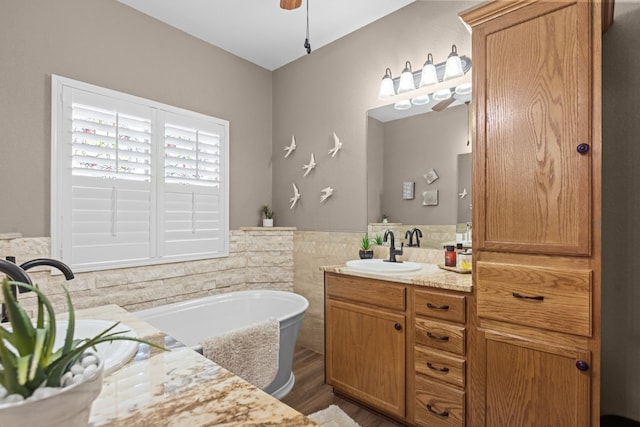 3960 Rabb St, Odessa, TX 79762 - full bathroom featuring vanity, a bath, wood finished floors, tile walls, and ceiling fan