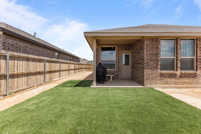 rear view of house featuring brick siding, a patio area, and a shingled roof