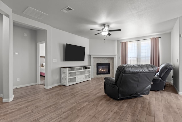 living room featuring wood finished floors, a ceiling fan, a glass covered fireplace, and baseboards