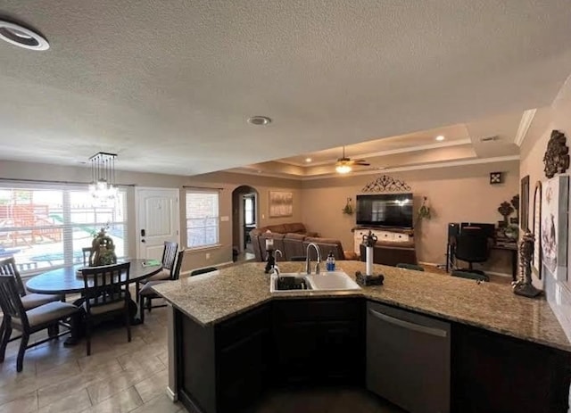 kitchen featuring a tray ceiling, light stone counters, stainless steel dishwasher, arched walkways, and a sink