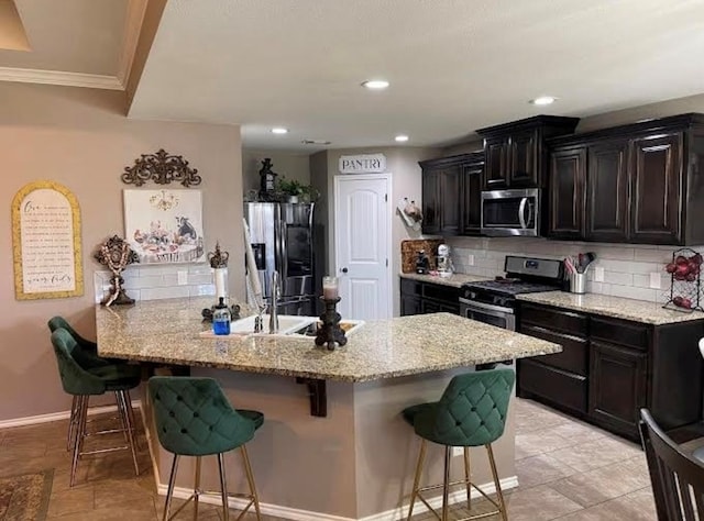 kitchen with a breakfast bar area, appliances with stainless steel finishes, tasteful backsplash, light stone counters, and kitchen peninsula