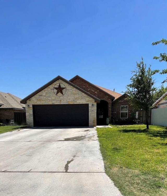 ranch-style house with fence, concrete driveway, a front yard, stone siding, and an attached garage