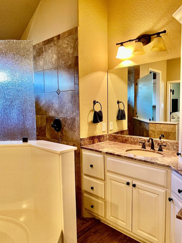 bathroom with vanity, a textured wall, walk in shower, and wood finished floors