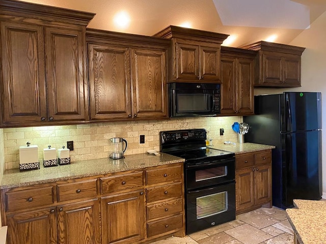 kitchen with decorative backsplash, stone tile floors, black appliances, and light stone countertops