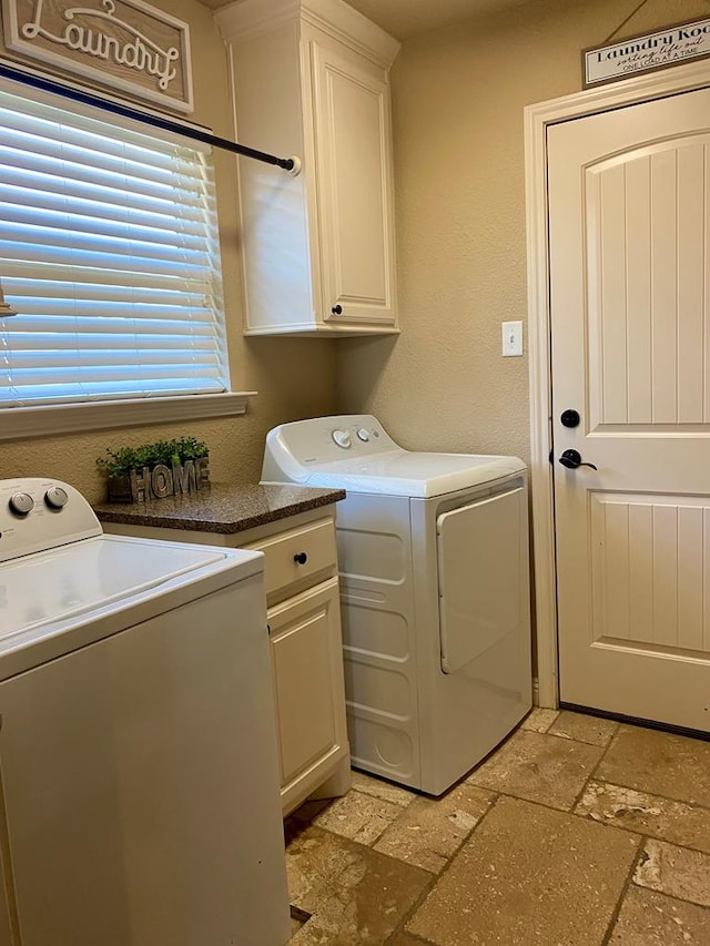 laundry room featuring stone tile floors, cabinet space, and washer and clothes dryer
