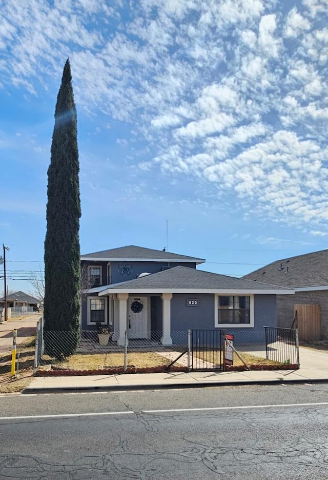 view of front of house featuring a fenced front yard, roof with shingles, and stucco siding