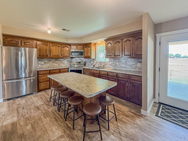 305 County Rd 306, Seminole, TX 79360 - kitchen with appliances with stainless steel finishes, a breakfast bar, light countertops, backsplash, and a textured ceiling