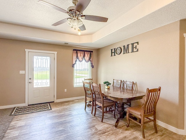 305 County Rd 306, Seminole, TX 79360 - dining area featuring ceiling fan, light wood-style flooring, a textured ceiling, and a raised ceiling