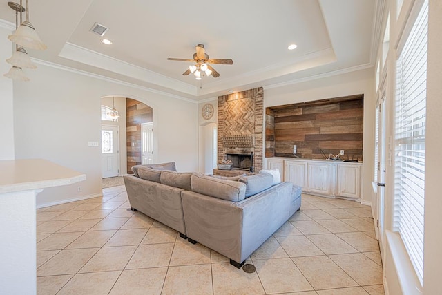 10901 E County Rd 108, Midland, TX 79706 - living room with a tray ceiling, light tile patterned flooring, arched walkways, a ceiling fan, and a large fireplace