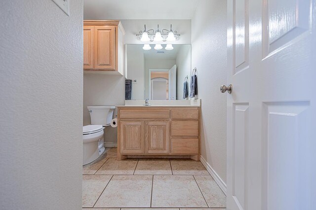 10901 E County Rd 108, Midland, TX 79706 - half bathroom with vanity, tile patterned flooring, toilet, a textured wall, and baseboards