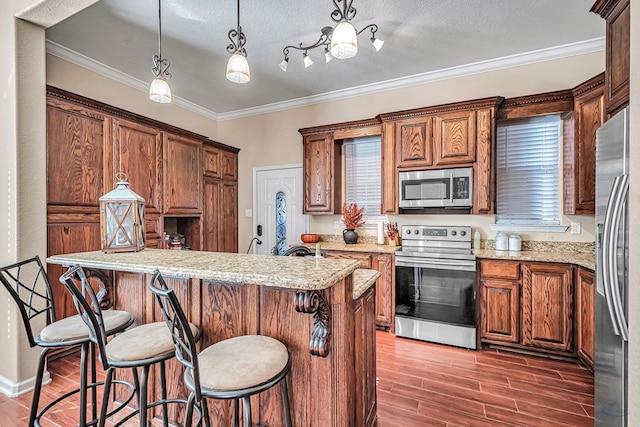 9540 W April St, Odessa, TX 79764 - kitchen featuring stainless steel appliances, wood finished floors, a breakfast bar area, crown molding, and a kitchen island
