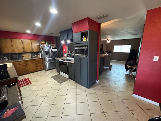 4417 Redbud Ave, Odessa, TX 79762 - kitchen with stainless steel appliances, light tile patterned flooring, brown cabinetry, a sink, and a ceiling fan