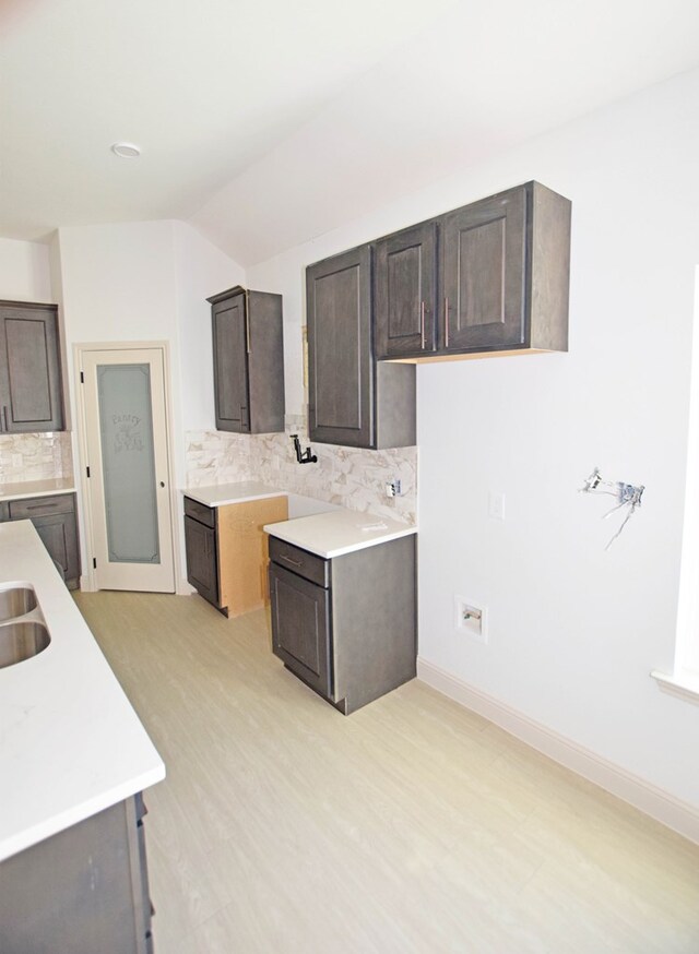 8639 Fortuna Ct, Odessa, TX 79765 - kitchen with dark brown cabinetry, backsplash, light countertops, light wood finished floors, and baseboards