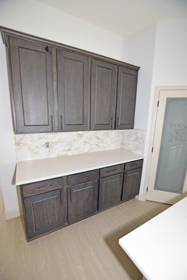 8639 Fortuna Ct, Odessa, TX 79765 - kitchen with dark brown cabinets, light countertops, decorative backsplash, and light wood-type flooring