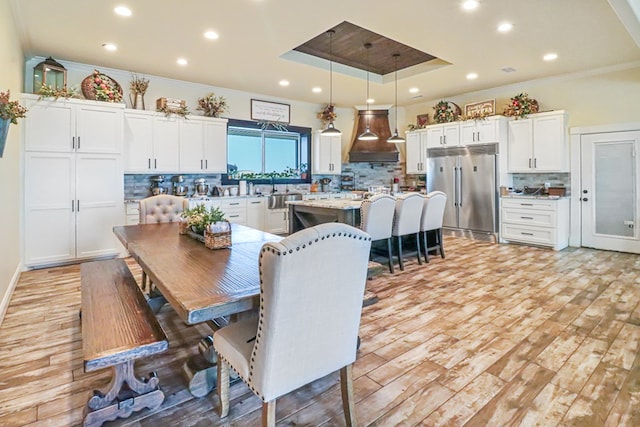 dining room with light hardwood / wood-style floors, ornamental molding, and a tray ceiling