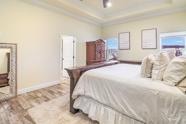 bedroom with light wood-type flooring, a raised ceiling, ceiling fan, and ornamental molding