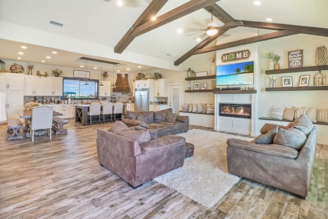 living room featuring ceiling fan, lofted ceiling with beams, and light hardwood / wood-style floors