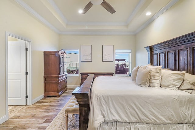 bedroom featuring a tray ceiling, ceiling fan, ornamental molding, and light wood-type flooring