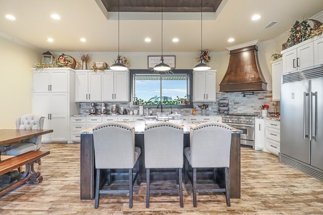 kitchen with custom exhaust hood, high end appliances, decorative backsplash, and light stone counters