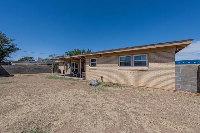 rear view of property featuring brick siding, a fenced backyard, and a patio area
