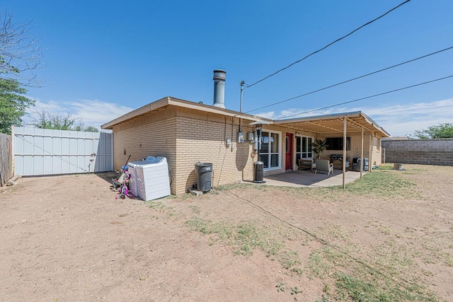 rear view of house featuring brick siding, fence, a patio area, and a gate