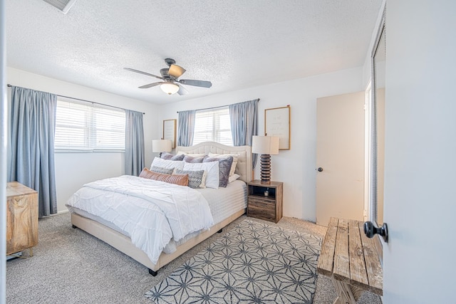 bedroom with light carpet, a textured ceiling, and a ceiling fan