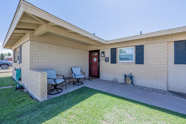 entrance to property featuring brick siding and a yard