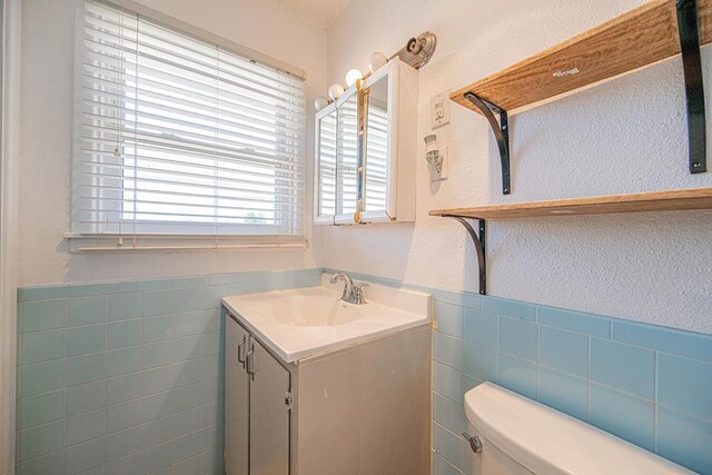 3502 Maple Ave, Odessa, TX 79762 - bathroom with tile walls, toilet, a textured wall, vanity, and wainscoting