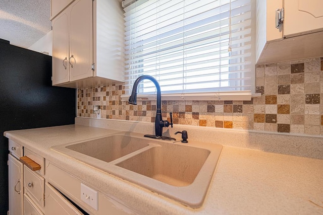 kitchen featuring a sink, white cabinetry, light countertops, backsplash, and freestanding refrigerator