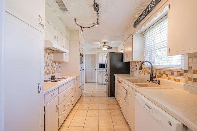 kitchen with stainless steel appliances, under cabinet range hood, a sink, a textured ceiling, and light tile patterned flooring
