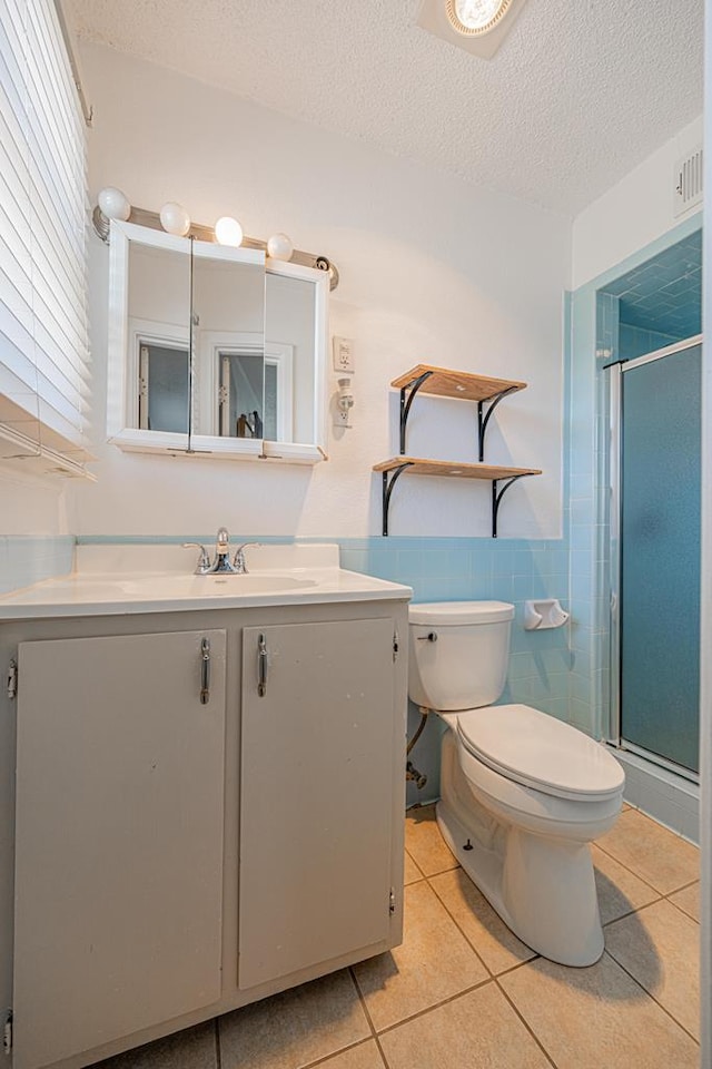 full bath with tile patterned flooring, vanity, a shower stall, toilet, and a textured ceiling