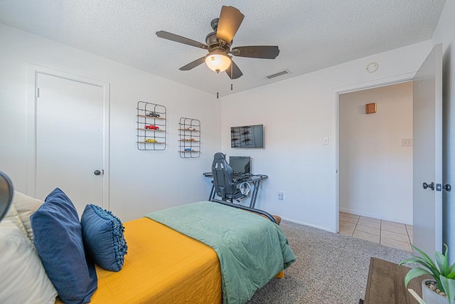 bedroom featuring a textured ceiling, carpet floors, tile patterned flooring, a ceiling fan, and baseboards