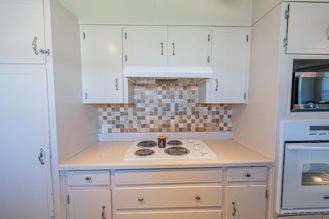 kitchen with white appliances, exhaust hood, white cabinets, and light countertops