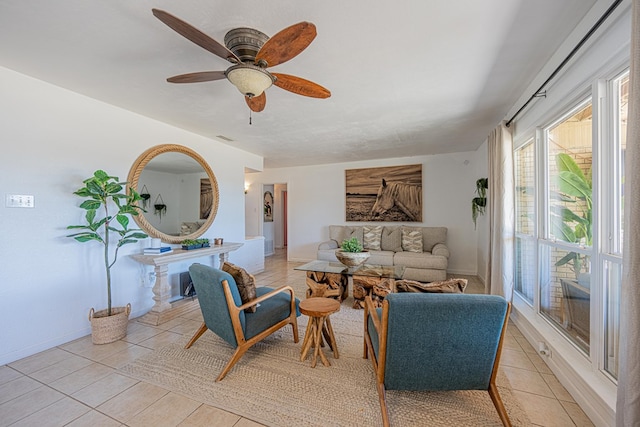living area with light tile patterned flooring, ceiling fan, and baseboards