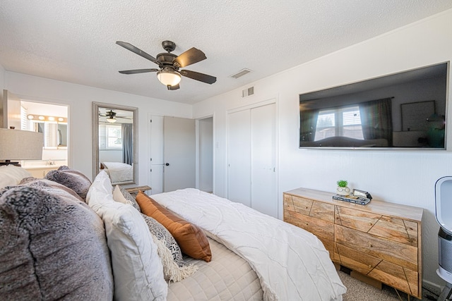 carpeted bedroom with multiple windows, a textured ceiling, a closet, ensuite bath, and ceiling fan