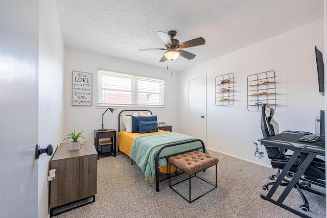 bedroom featuring a desk, a textured ceiling, light colored carpet, a ceiling fan, and baseboards