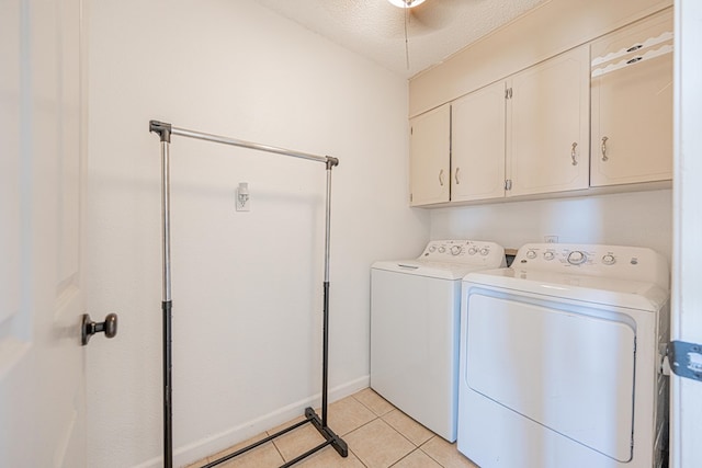 laundry room with cabinet space, washing machine and clothes dryer, a textured ceiling, light tile patterned floors, and baseboards