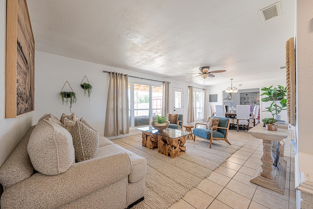 living room featuring light tile patterned flooring, a ceiling fan, and a chandelier