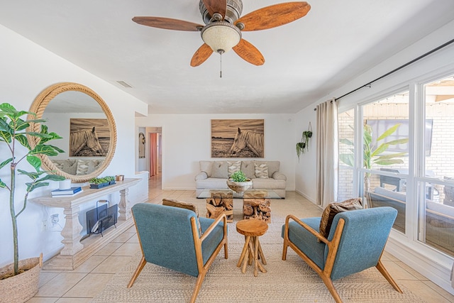 living area with light tile patterned floors, baseboards, and ceiling fan