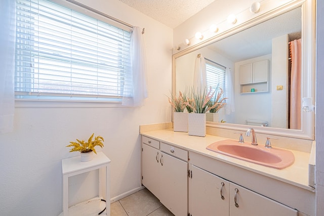 bathroom with toilet, vanity, tile patterned floors, a textured ceiling, and baseboards