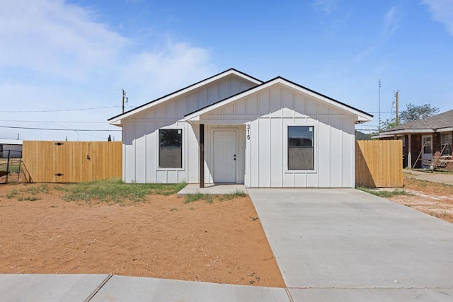 view of front of property featuring fence, board and batten siding, and concrete driveway
